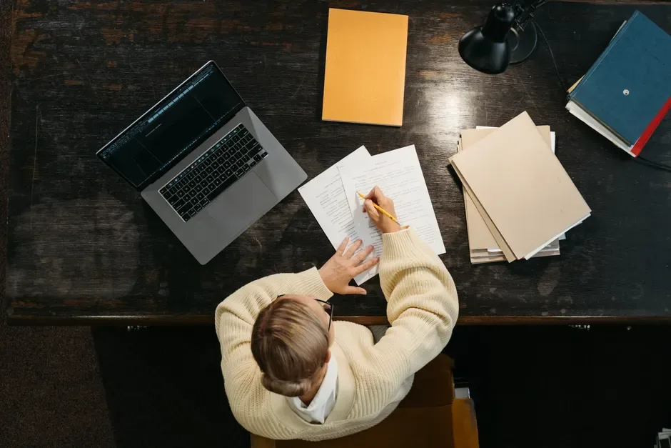 Writer working on localised content with laptop, papers, and research notes